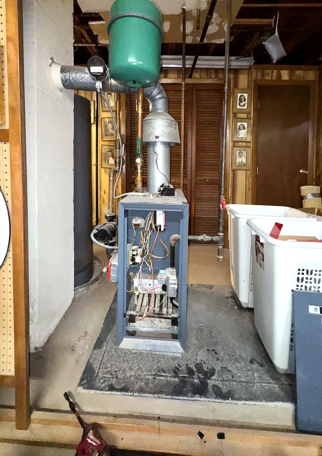 Old boiler with green expansion tank in a cluttered basement
